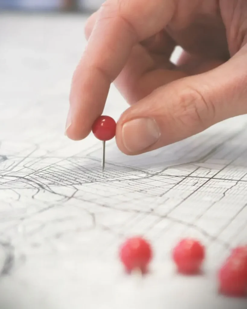 Hand pinnt einen Pin an eine Landkarte