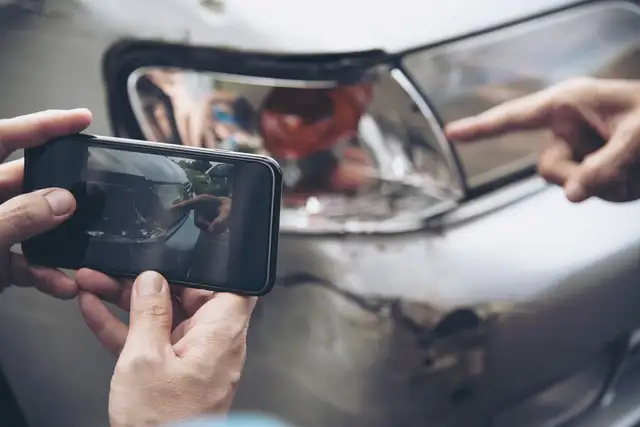 Beschädigtes Fahrzeug wird nach einem Verkehrsunfall mit dem Smartphone fotografiert